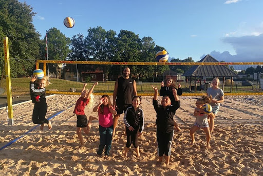 Barn på beachvolleyplan hoppar och kastar bollar i luften. Foto: KFUM Kristianstad VK
